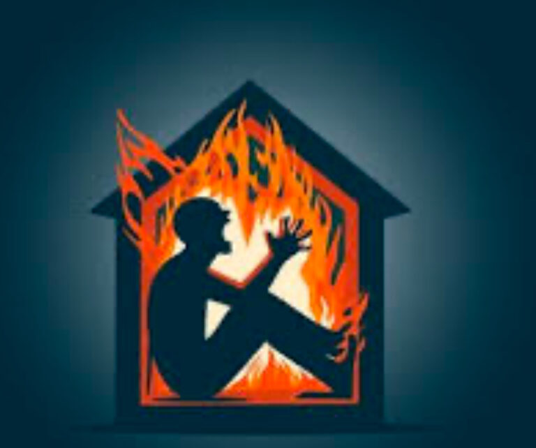 man sits inside a house on fire